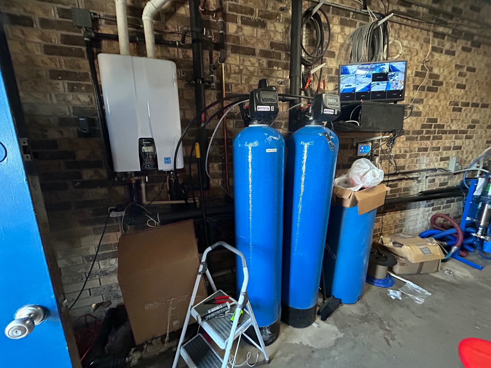 Blue water treatment tanks and controls inside a carwash equipment room